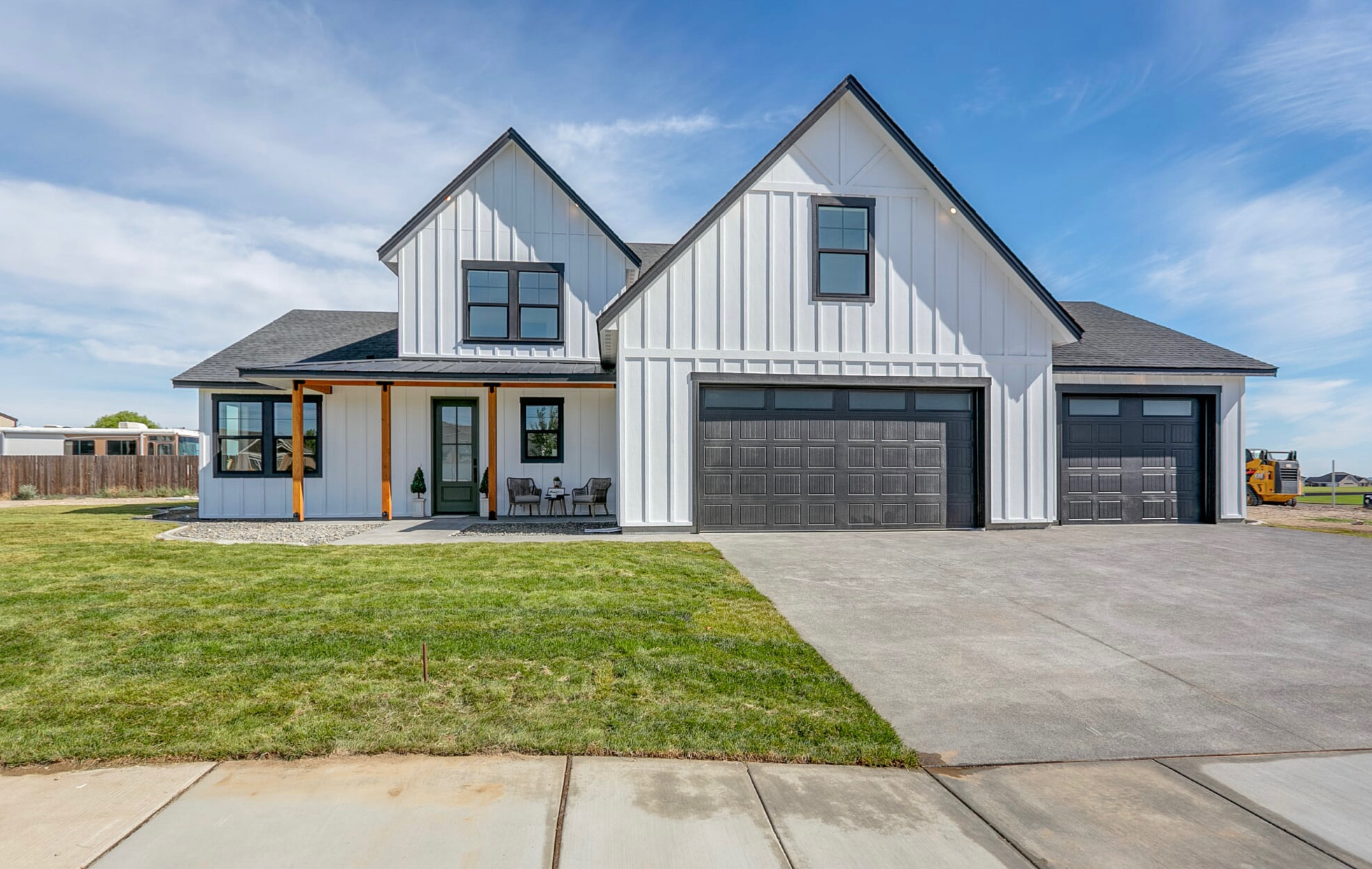 White farmhouse exterior with black trim, wood porch posts and three-car garage
