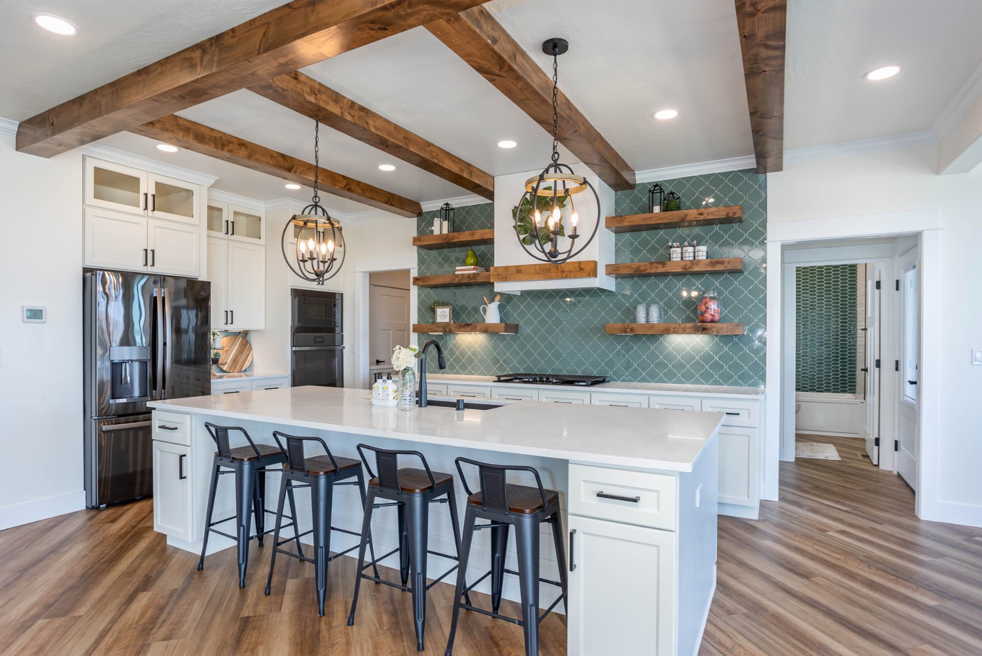 Kitchen with wood-beamed ceiling, large island and green tiled backsplash