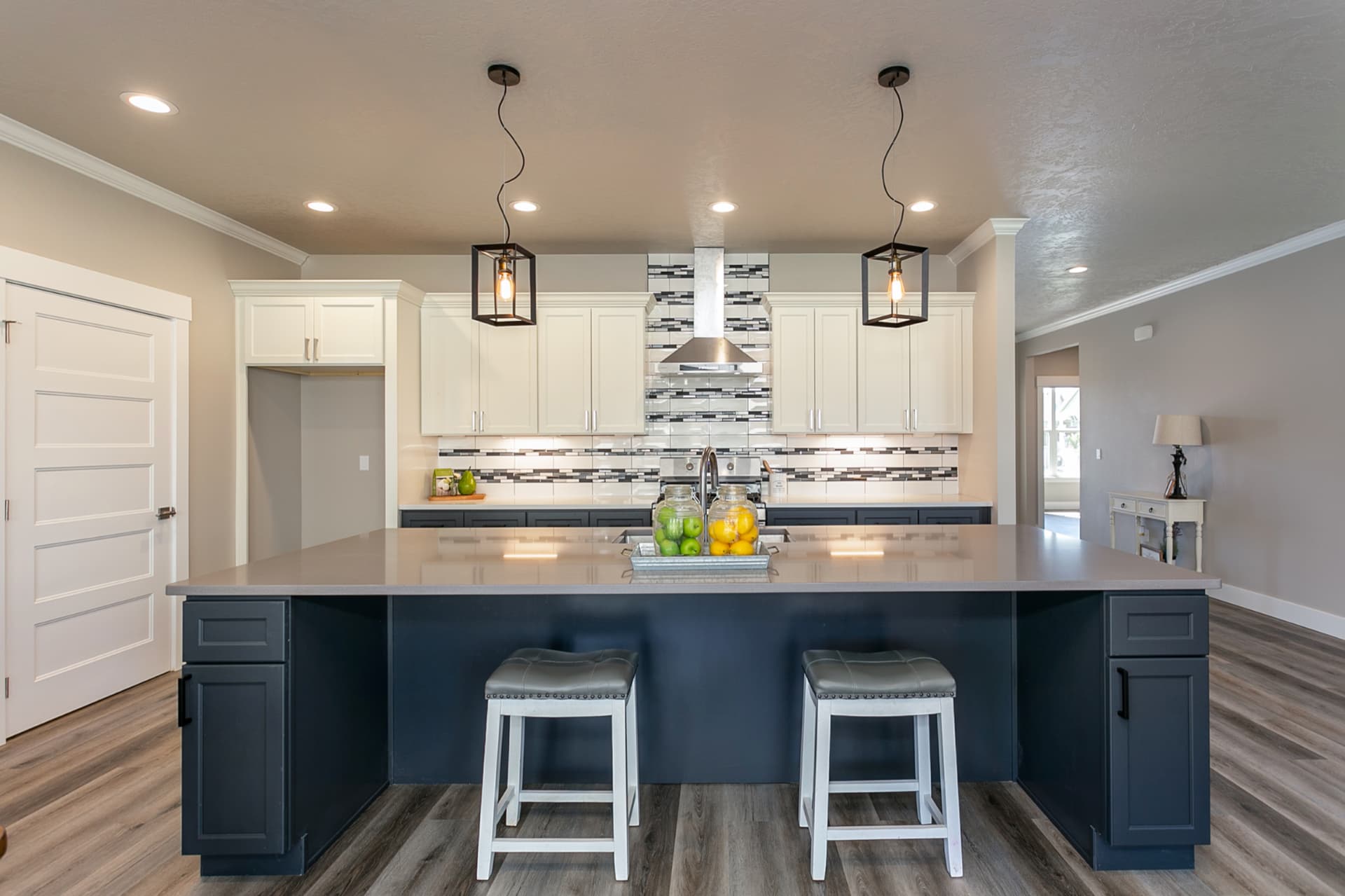Kitchen with navy island, white cabinets and glass pendant lights